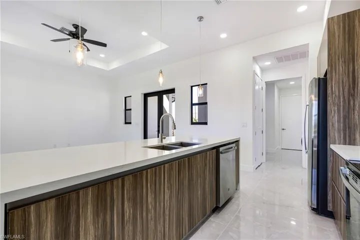 Kitchen featuring modern cabinets, recessed lighting, decorative light fixtures, stainless steel appliances, and a raised ceiling