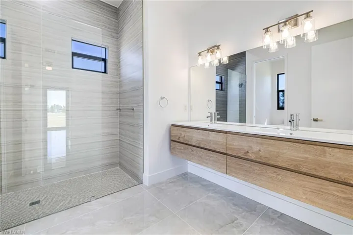 Full bath featuring double vanity and tiled shower