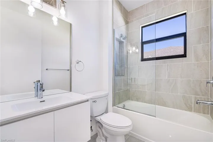 Full bathroom with combined bath / shower with glass door, vanity, and tile patterned flooring