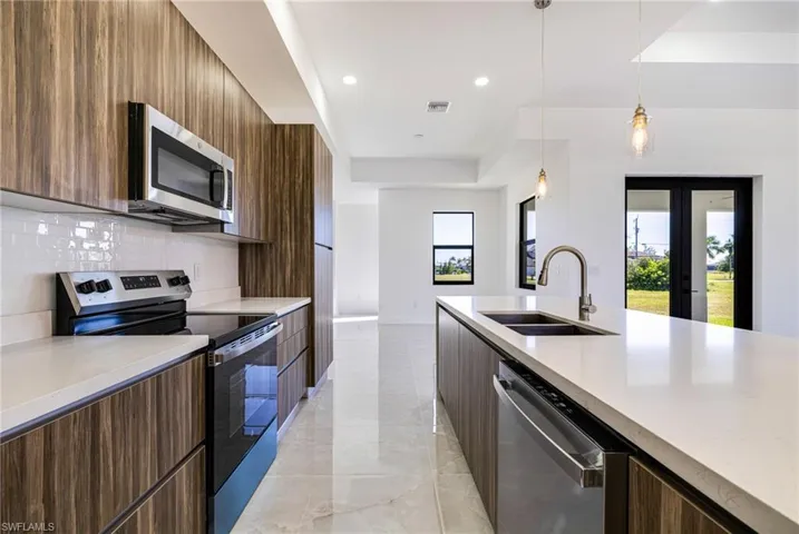 Kitchen featuring stainless steel appliances, modern cabinets, pendant lighting, light stone countertops, and recessed lighting