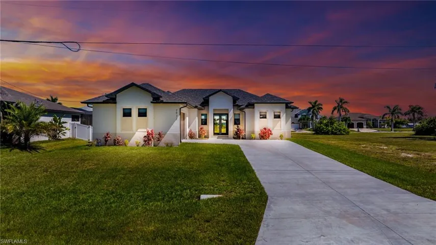 View of front of house with stucco siding, concrete driveway, and a front yard