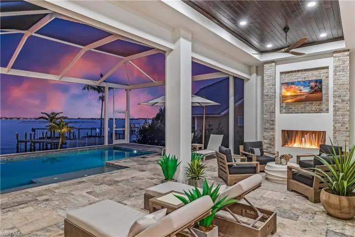 Pool at dusk featuring a fireplace and a water view