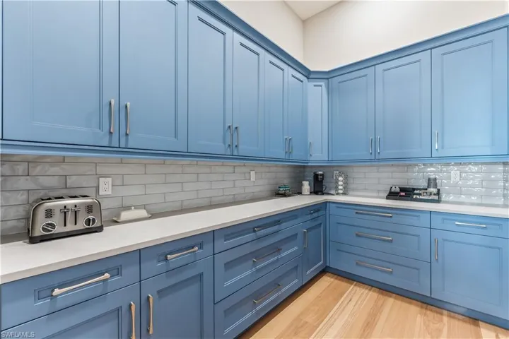 Kitchen with blue cabinetry, backsplash, and light hardwood / wood-style flooring