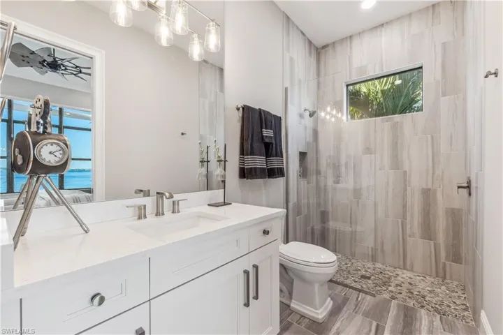 Bathroom with vanity, toilet, a water view, and a tile shower