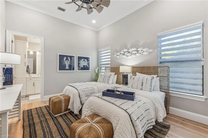 Bedroom with multiple windows, ceiling fan, light hardwood / wood-style flooring, and ensuite bathroom
