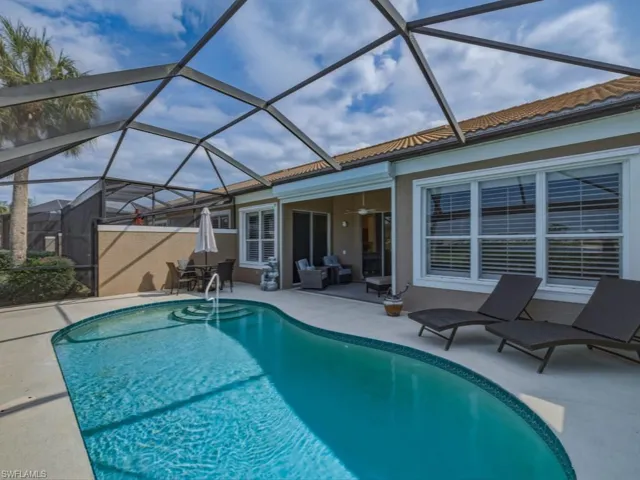 Outdoor pool featuring a sunroom, glass enclosure, and a patio