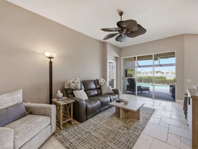 Living area with a ceiling fan, stone tile floors, and a sunroom