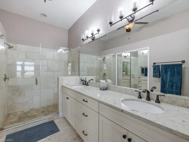 Full bathroom with ceiling fan, double vanity, and a shower stall