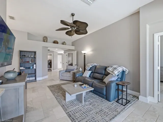 Living room with a ceiling fan, stone tile floors, and washer / dryer