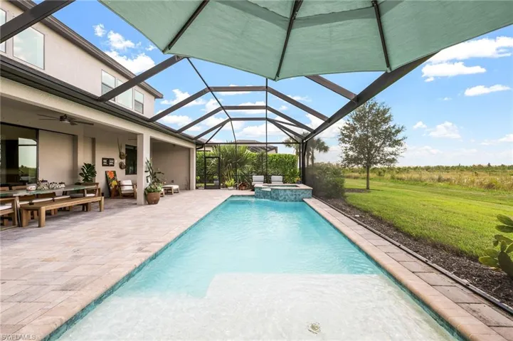 View of pool featuring ceiling fan, a lanai, an in ground hot tub, a patio, and a lawn