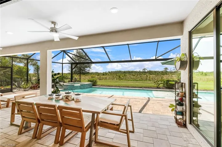 View of pool featuring ceiling fan, an in ground hot tub, glass enclosure, and a patio