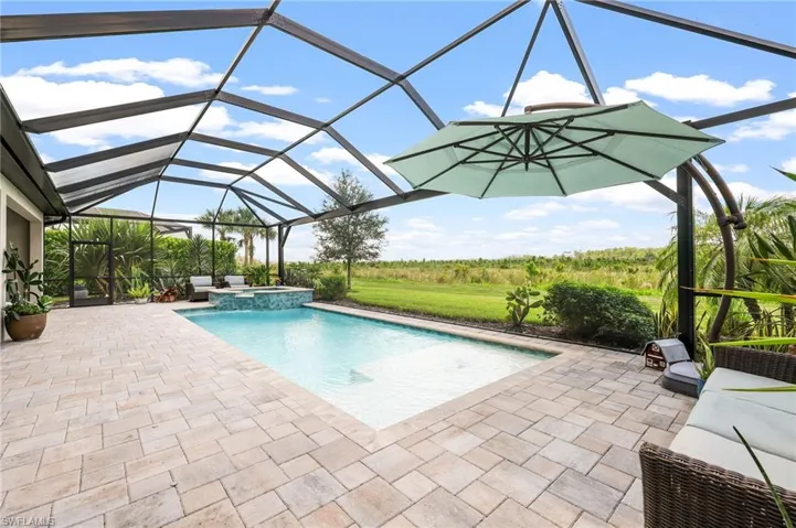 View of pool with an in ground hot tub, a patio area, and a lanai