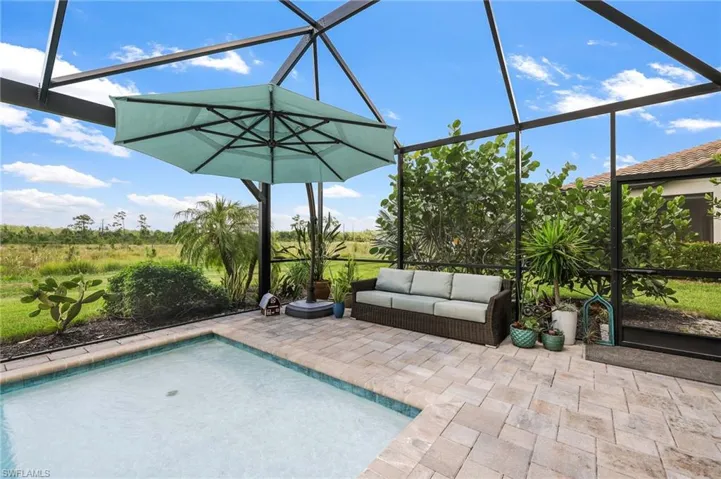 View of swimming pool featuring glass enclosure and a patio