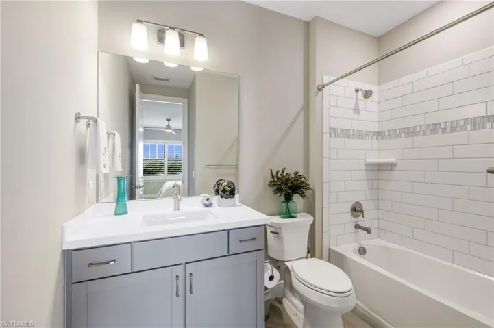 Full bathroom with vanity, tiled shower / bath combo, and toilet