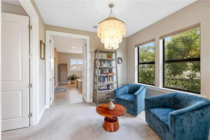 Living area featuring light tile patterned flooring, an inviting chandelier, and plenty of natural light