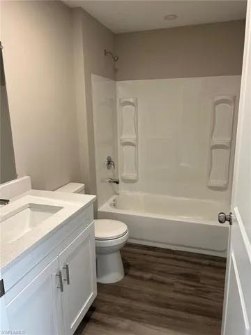 Full bath with vanity, dark wood finished floors, and tub / shower combination