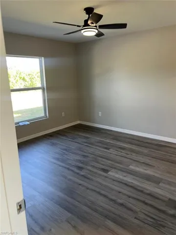 Unfurnished room featuring dark wood finished floors and a ceiling fan