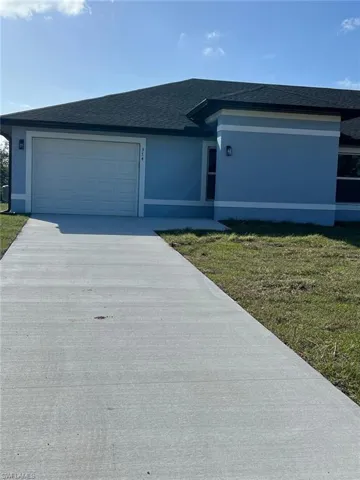 View of front of property featuring a front lawn, a shingled roof, a garage, and stucco siding