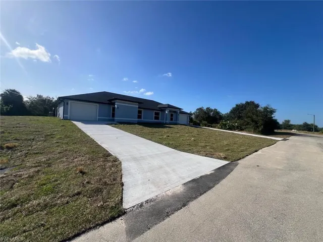 View of front of home featuring a front lawn, an attached garage, and driveway