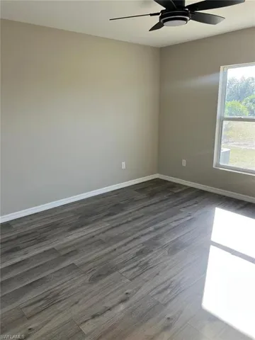 Unfurnished room with dark wood-style flooring and ceiling fan
