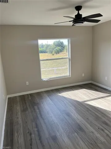 Spare room featuring ceiling fan and dark wood-style floors