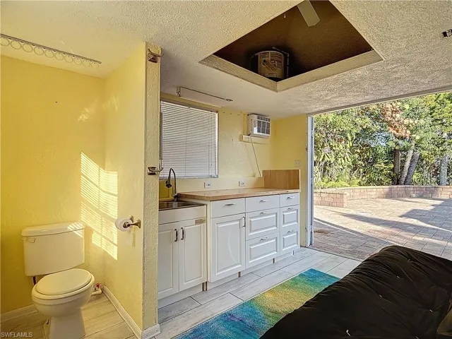 Bathroom featuring vanity, a textured ceiling, a textured wall, ceiling fan, and wood tiled floors
