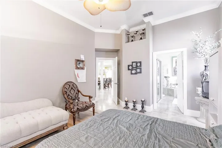 Bedroom featuring crown molding, ensuite bathroom, a towering ceiling, and a ceiling fan