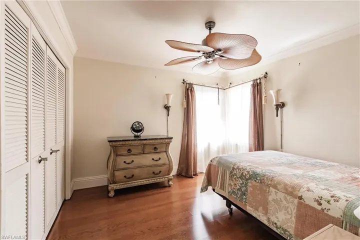 Bedroom with a closet, wood finished floors, crown molding, and ceiling fan