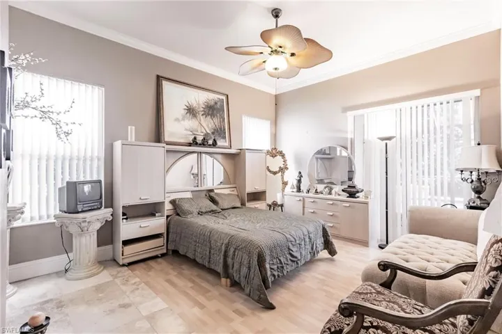 Bedroom with ornamental molding, ceiling fan, and light wood-style flooring