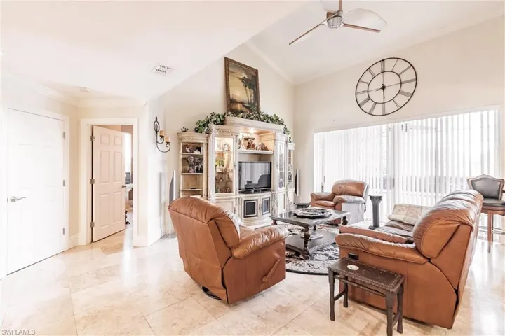 Living room featuring ceiling fan, vaulted ceiling, and crown molding