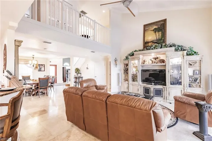 Living area featuring a ceiling fan, a chandelier, and a towering ceiling
