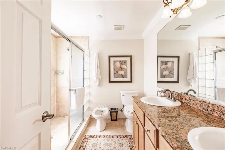 Bathroom featuring a bidet, a stall shower, double vanity, tile patterned floors, and crown molding