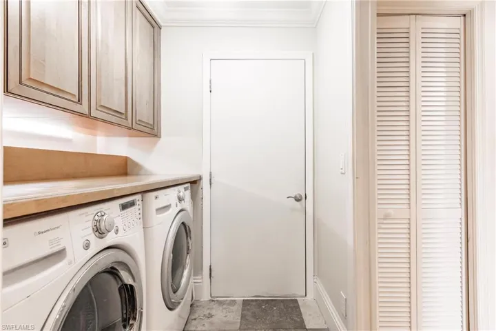 Laundry room with washing machine and dryer, cabinet space, and crown molding
