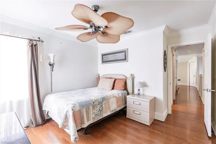 Bedroom featuring crown molding, wood finished floors, and a ceiling fan