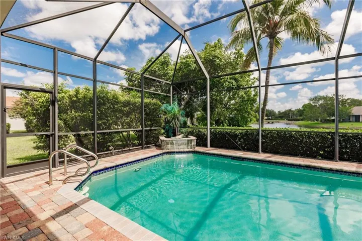 Swimming pool with a water view, a lanai, a patio, and view of wooded area