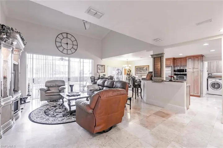 Living area featuring washer / clothes dryer, ornate columns, a chandelier, recessed lighting, and high vaulted ceiling