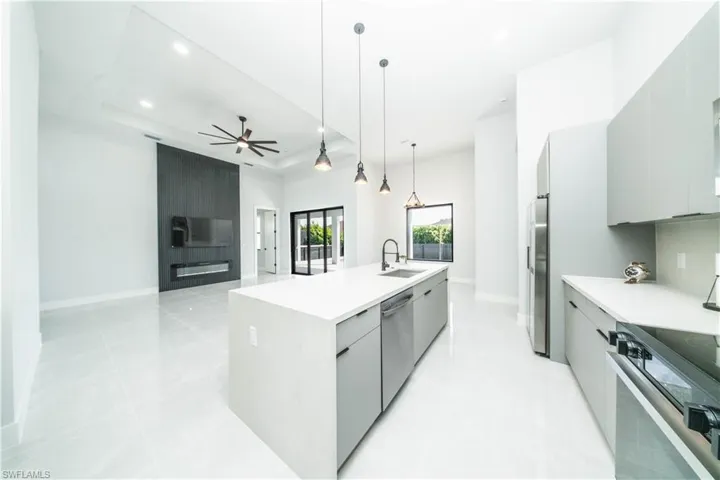 Kitchen with gray cabinetry, modernan cabinets, open floor plan, a center island with sink, and a raised ceiling