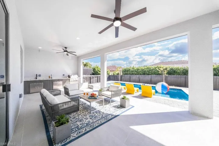 View of swimming pool featuring exterior kitchen, patio surround, and a fenced backyard