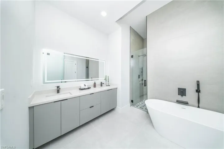 Full bathroom featuring a shower stall, double vanity, a soaking tub, light tile patterned floors, and recessed lighting