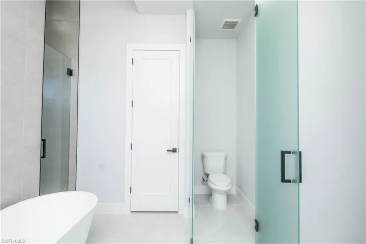 Bathroom featuring light tile patterned floors, a freestanding bath, and a shower stall