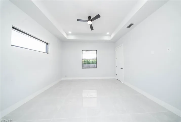 Spare room featuring ceiling fan, a raised ceiling, recessed lighting, and light tile patterned flooring
