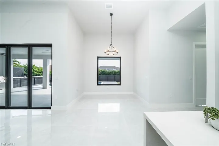 Unfurnished dining area with hanlging lights and baseboards