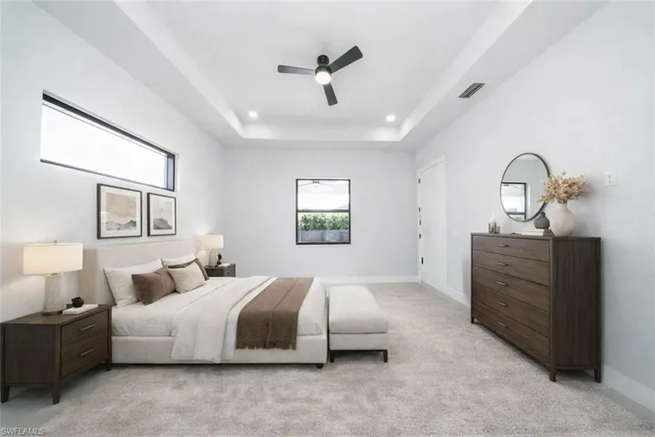 Bedroom with ceiling fan, light colored carpet, a tray ceiling, and recessed lighting