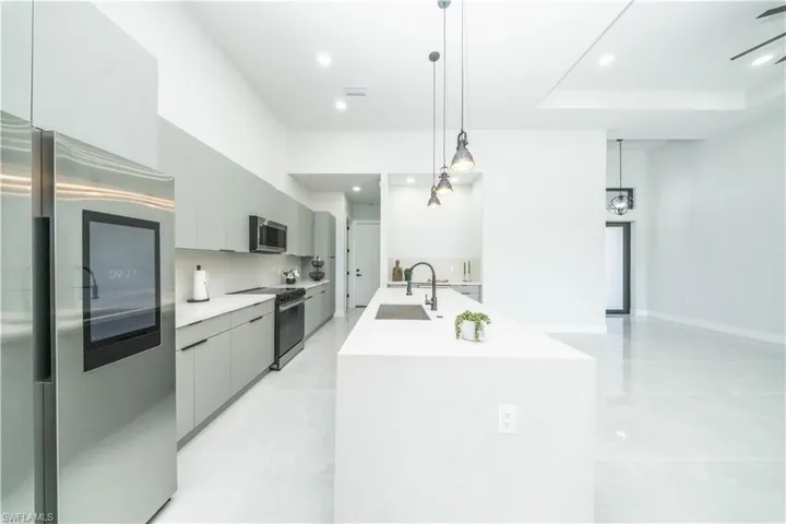 Kitchen with stainless steel appliances, gray cabinets, decorative light fixtures, and modern cabinets