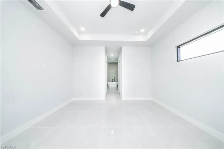 Empty room featuring ceiling fan, a raised ceiling, and recessed lighting