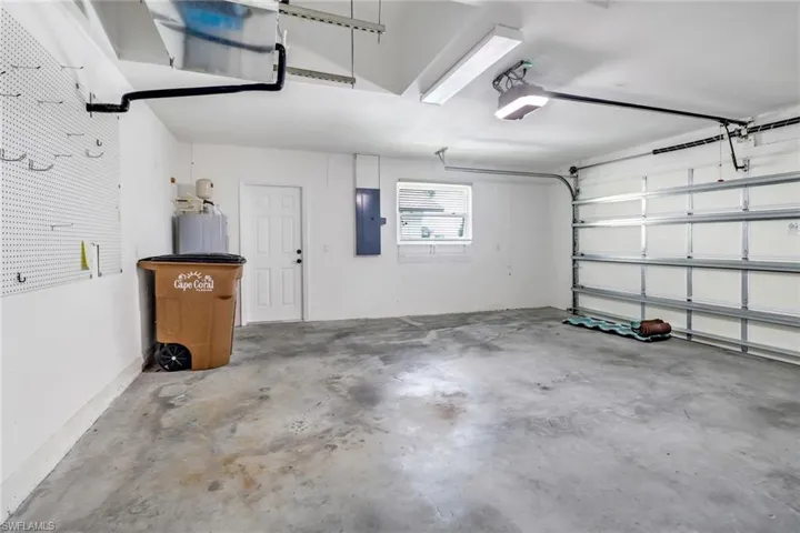 Garage with electric panel, water heater, and a garage door opener