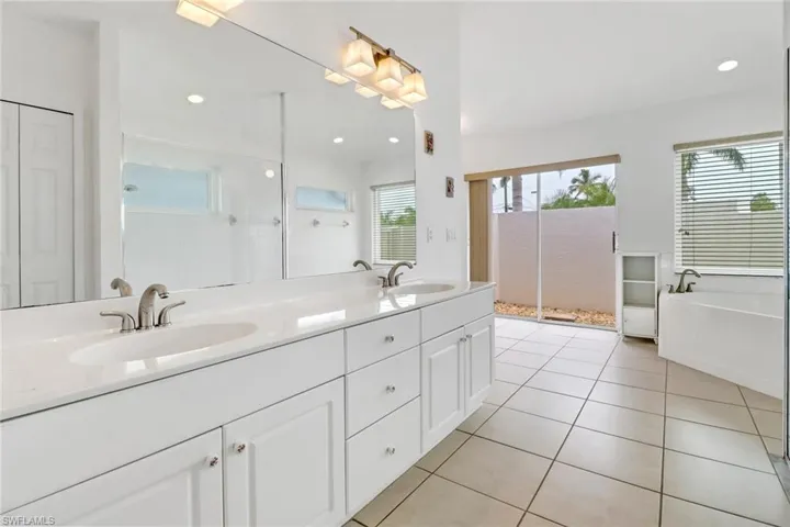 Bathroom with dual vanity, shower with separate bathtub, tile patterned flooring, and a healthy amount of sunlight