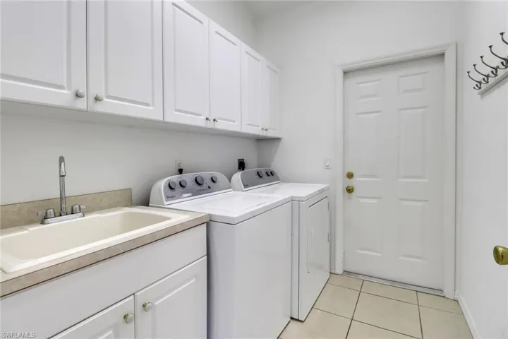 Laundry room featuring cabinets, washer and dryer, sink, and light tile patterned floors