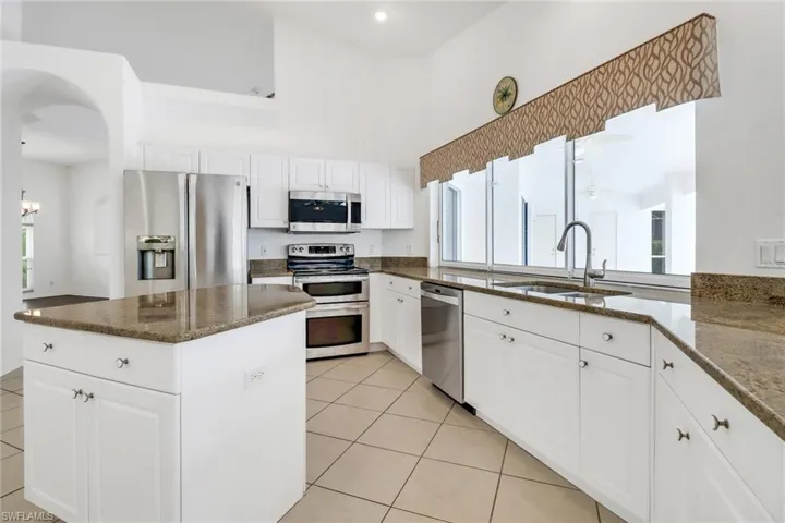 Kitchen with white cabinetry, light tile patterned floors, a wealth of natural light, appliances with stainless steel finishes, and sink
