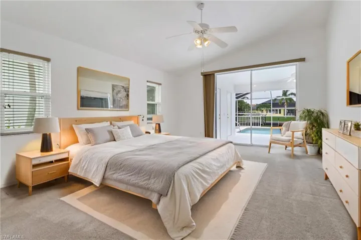 Master bedroom with access to exterior, ceiling fan, and vaulted ceiling
